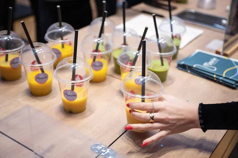 Health & Mind Festival: Vibrant Smoothie Station with Colorful Drinks and Participant's Hand
