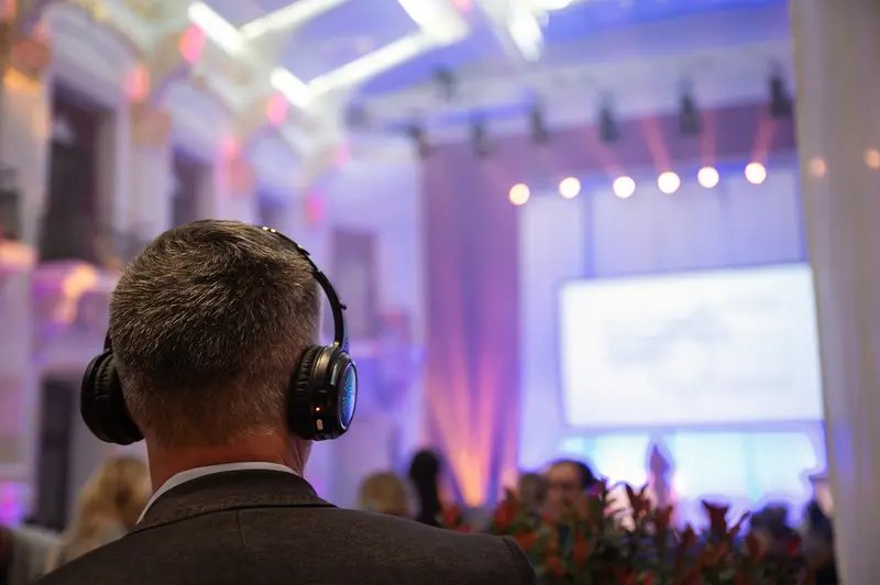 Health & Mind Festival: Attendee with Headphones Observing Presentation Stage