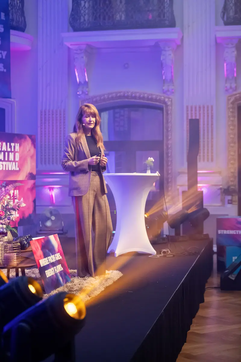Health & Mind Festival: Speaker Presenting on Illuminated Stage with Purple Ambiance