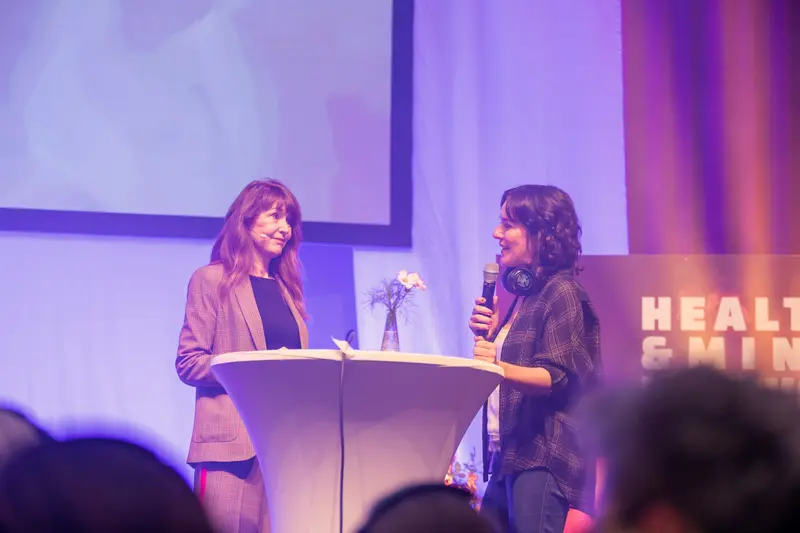 Health & Mind Festival: Two Women Engage in Dialogue on Illuminated Stage