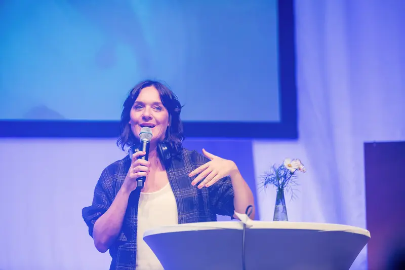 Speaker Presenting at Health & Mind Festival Under Blue Stage Lighting