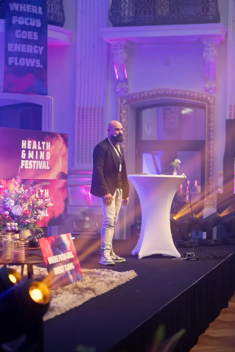 Health & Mind Festival: Speaker on Purple-Lit Stage in Classical Interior