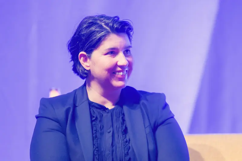 Speaker Smiling at Health & Mind Festival Against Purple-Tinted Stage Backdrop
