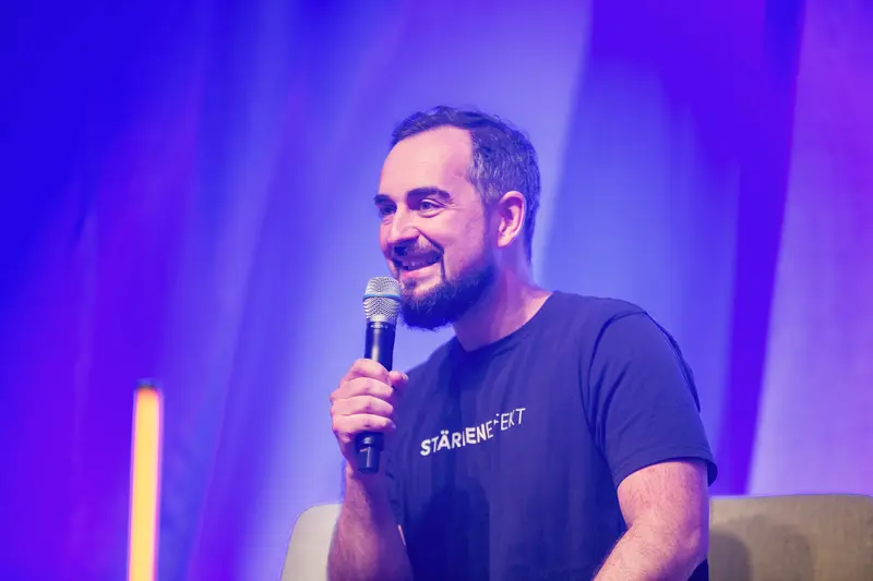 Speaker Presenting at Health & Mind Festival Under Purple Stage Lighting