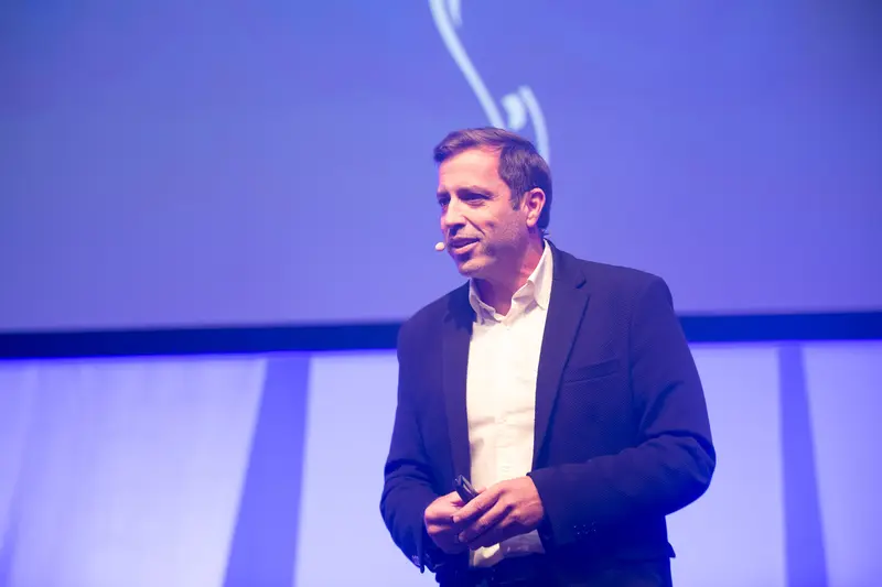Speaker Presenting at Health & Mind Festival Under Blue Stage Lighting
