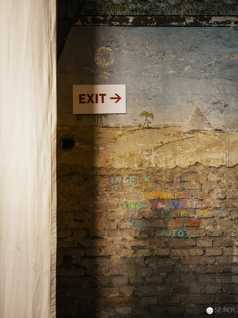 Exit Sign in Weathered Urban Interior with Graffiti and Faded Brick Wall