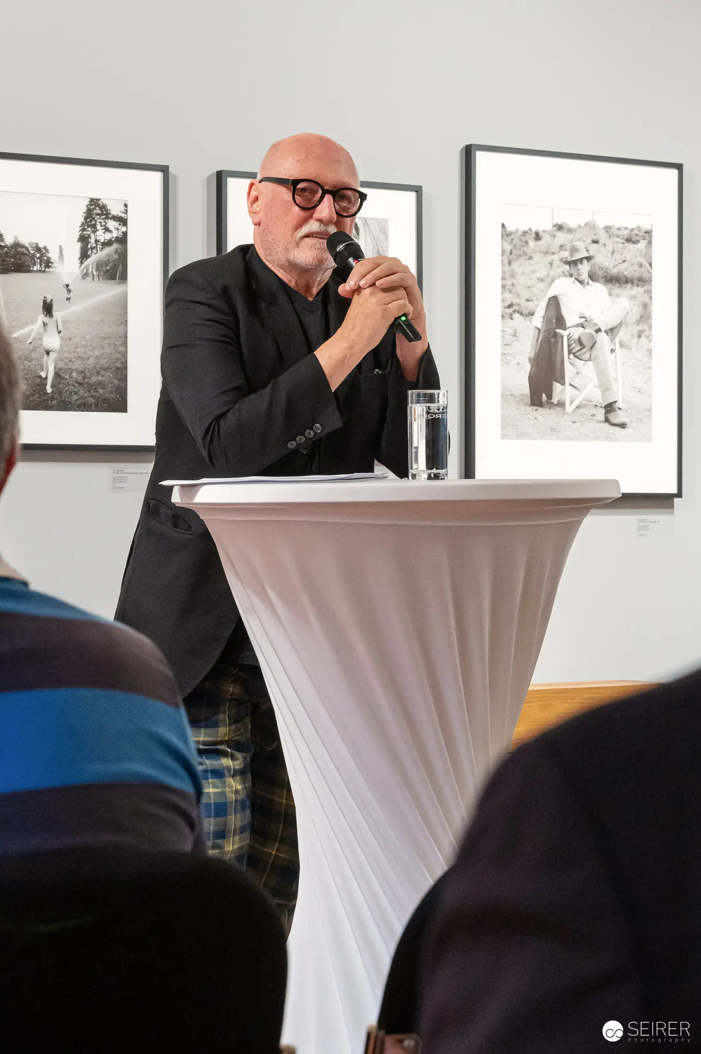 Distinguished Speaker Presenting at Gallery Exhibition with Black and White Photography