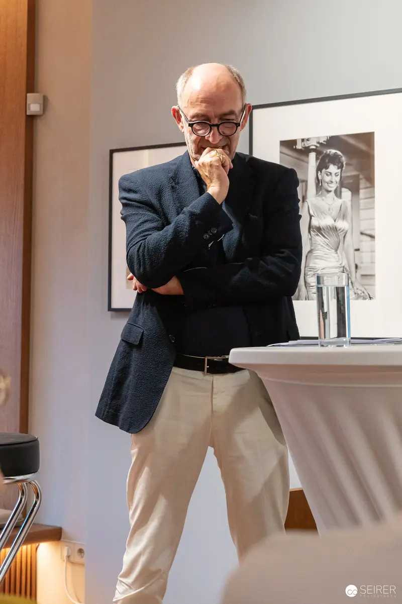 Reflective Older Male in Gallery Space with Photographic Portrait