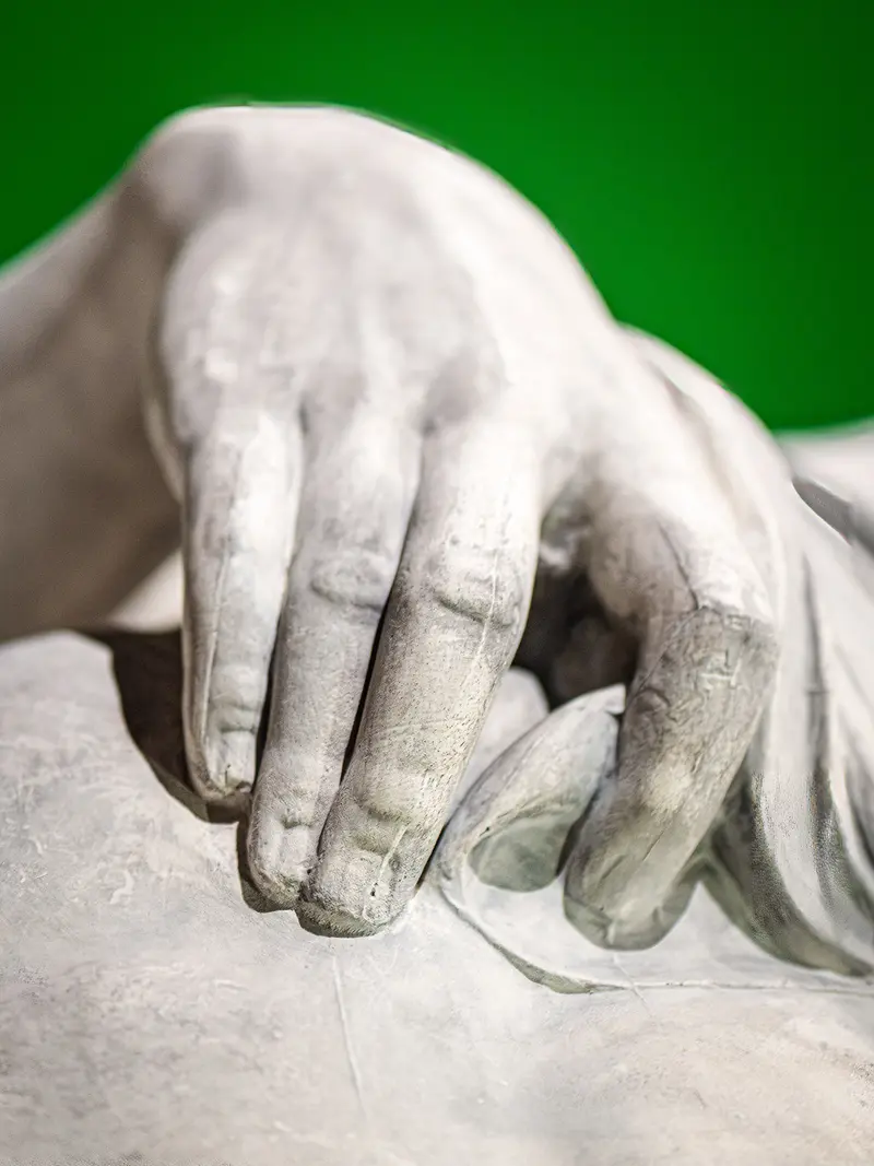 Marble Hand Sculpture Revealing Delicate Sculptural Form Against Green Background