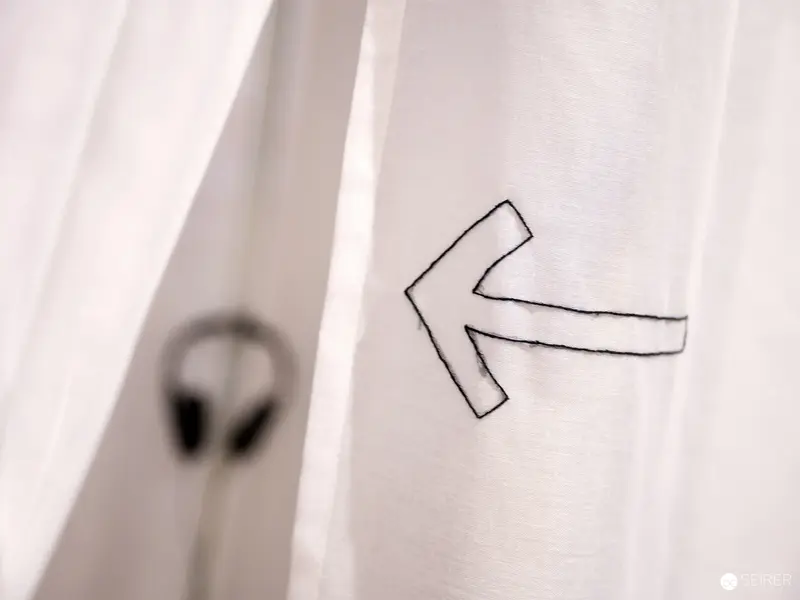 Minimalist Arrow Sign on White Wall with Blurred Object