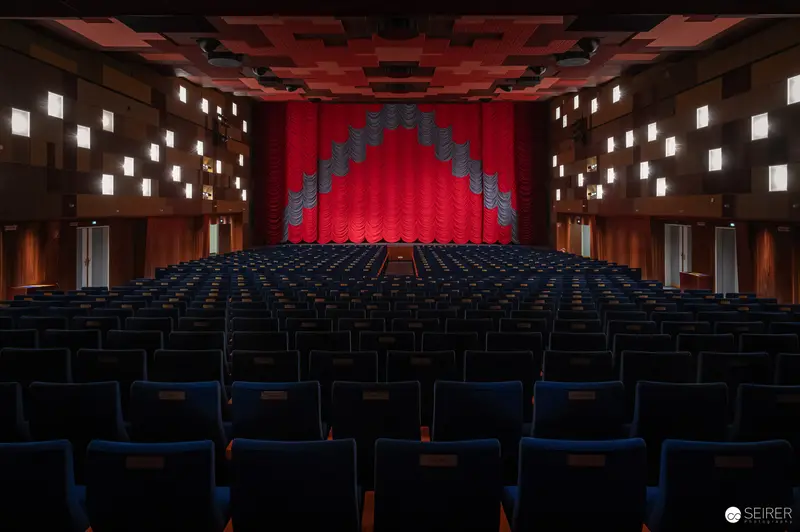 Empty Cinema Hall with Red Curtain Stage and Geometric Lighting Design