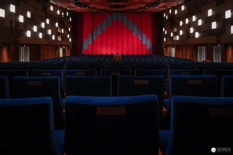 Empty Cinema Interior with Vibrant Red Stage and Blue Seating