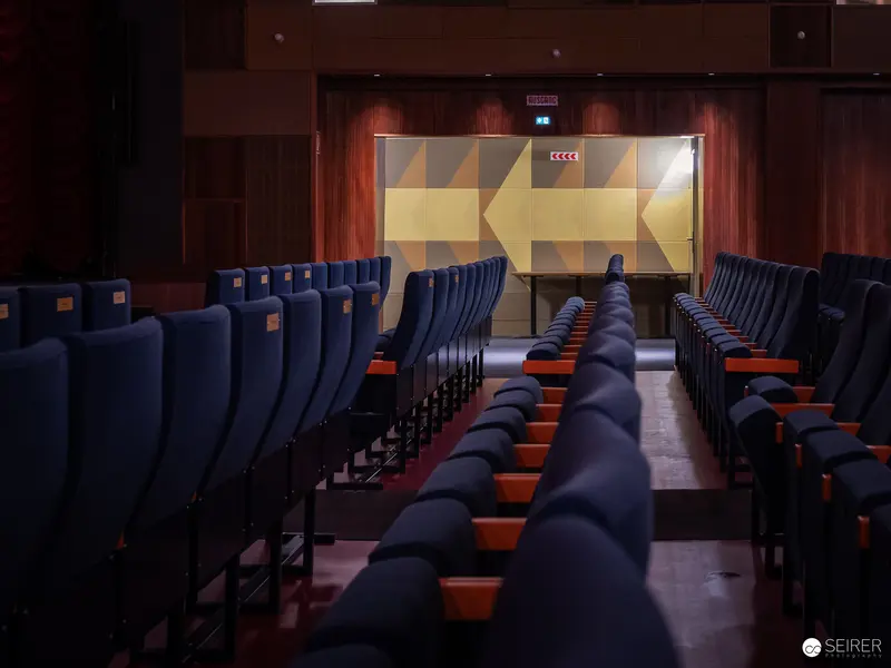 Empty Cinema Hall with Geometric Wall Art and Blue Seating Rows