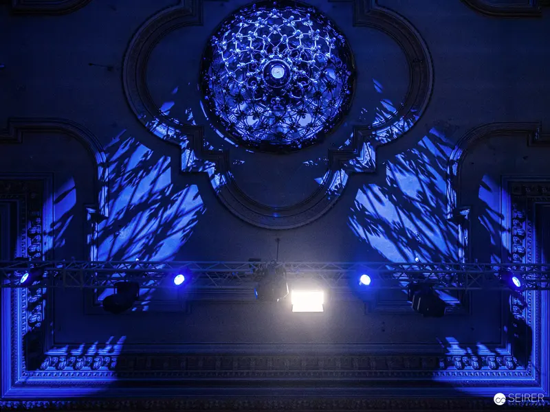 Illuminated Geometric Chandelier in Blue-Toned Architectural Performance Space