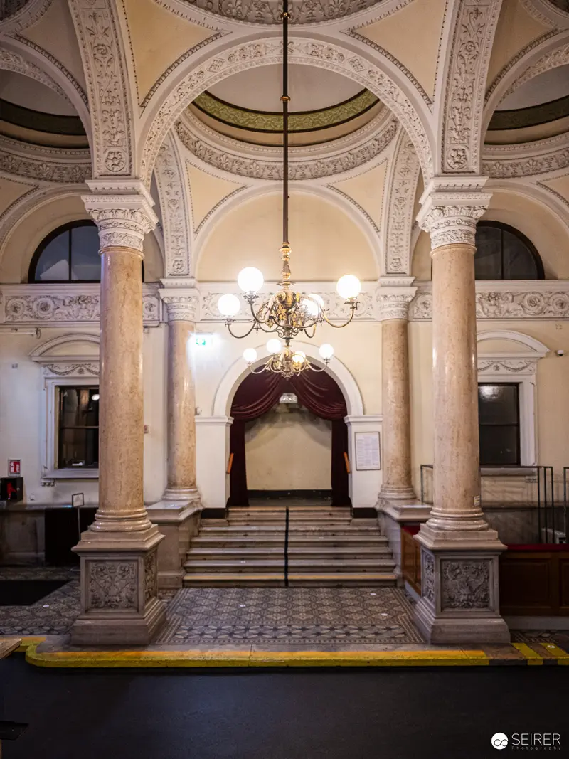 Ornate Architectural Interior with Chandelier and Marble Columns at Historic Venue