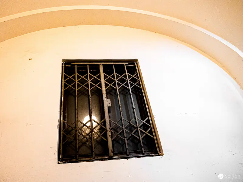 Barred Window in Arched Wall with Geometric Metal Grate