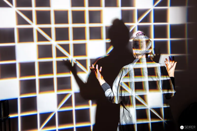 Silhouetted Performance with Geometric Light Projection and Grid Background
