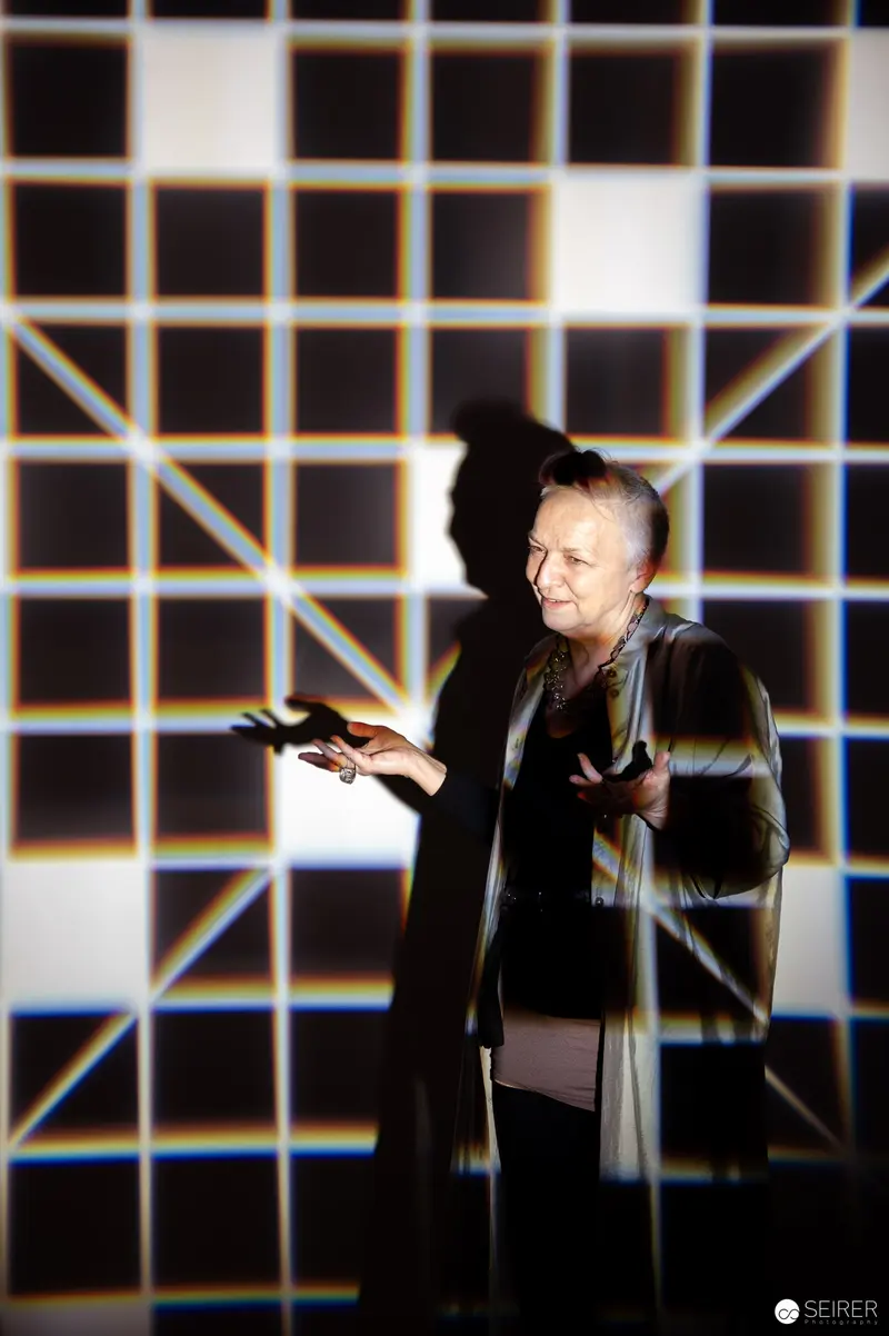 Performer Gesturing on Stage with Geometric Light Grid Background