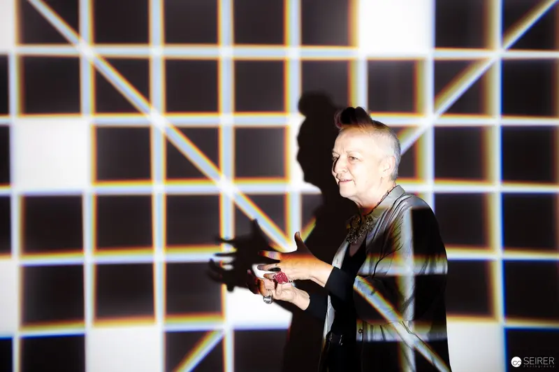 Performer Gesturing Against Geometric Gridded Light Installation Backdrop