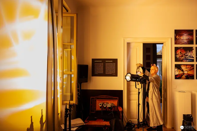 Photographer Adjusting Studio Lighting in Warm Amber Interior Setting