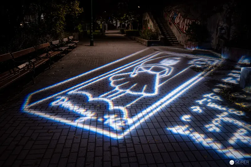 Luminescent Urban Pictogram Projection on Nighttime Brick Plaza Walkway