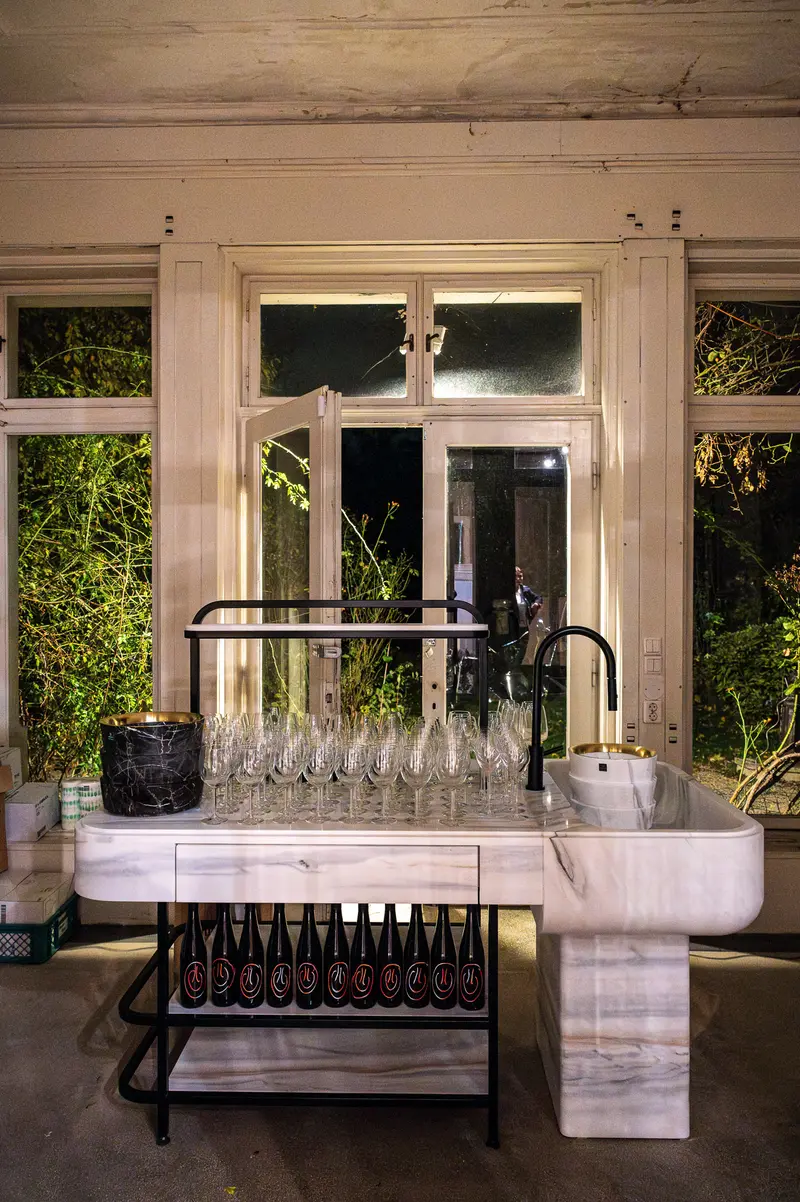 Marble Kitchen Station with Wine Bottles and Glassware near Garden Windows