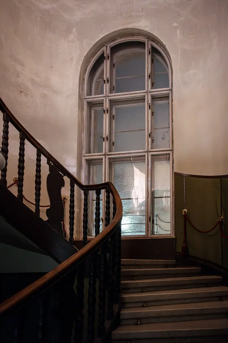 Architectural Interior with Curved Staircase and Arched Window in Muted Tones