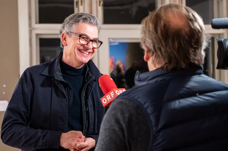 ORF Radio Interview with Smiling Guest in Dark Coat and Glasses