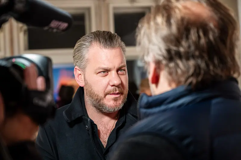 Media Interview with Gray-Haired Man in Black Shirt at Press Event