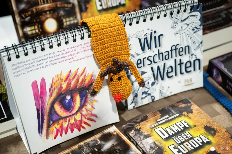 Crocheted Creature Amid Art Books and Colorful Eye Illustration