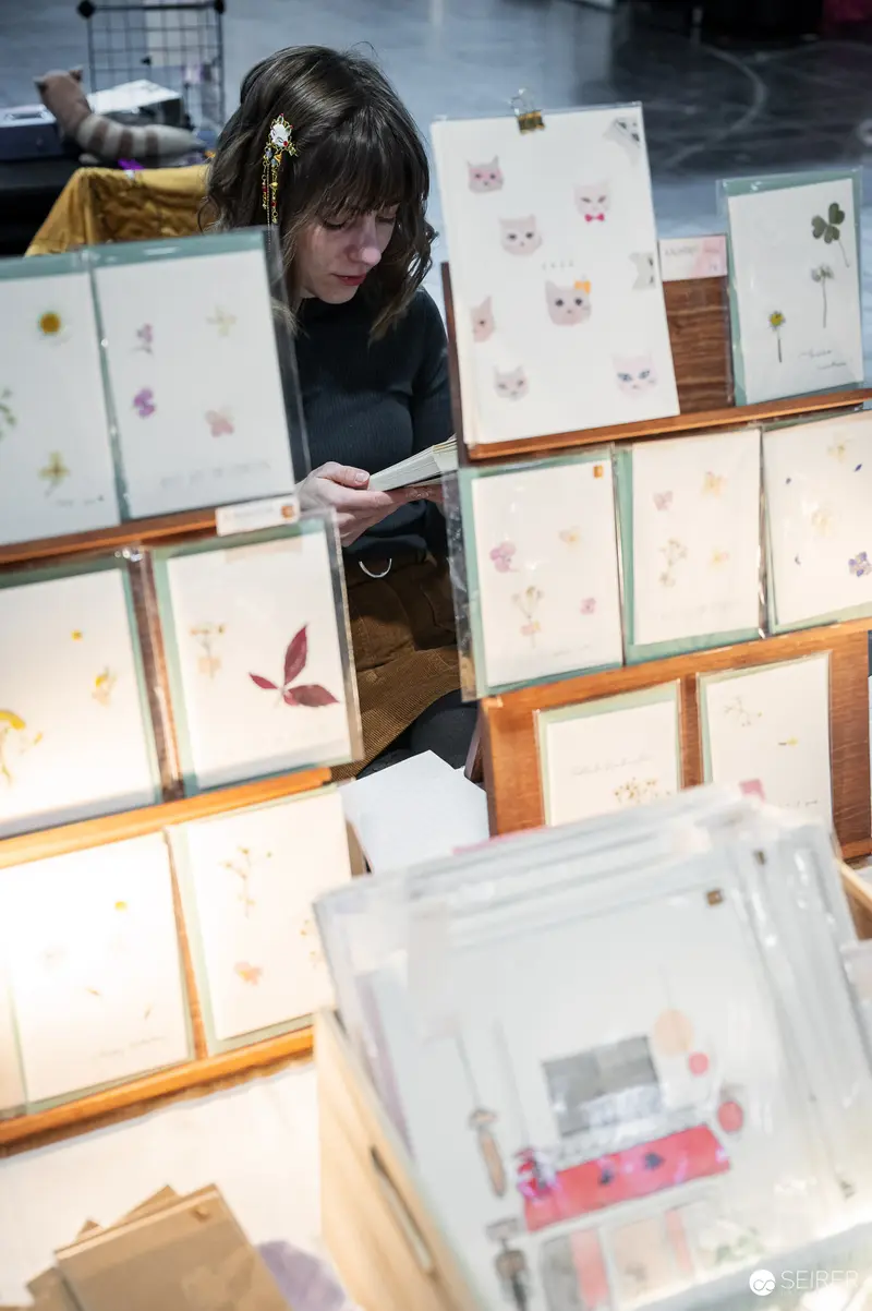 Introspective Viewer Examining Delicate Framed Artwork in Exhibition Space
