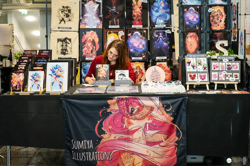 Sumiya Illustrations Artist at Exhibition Booth Displaying Vibrant Artwork Collection