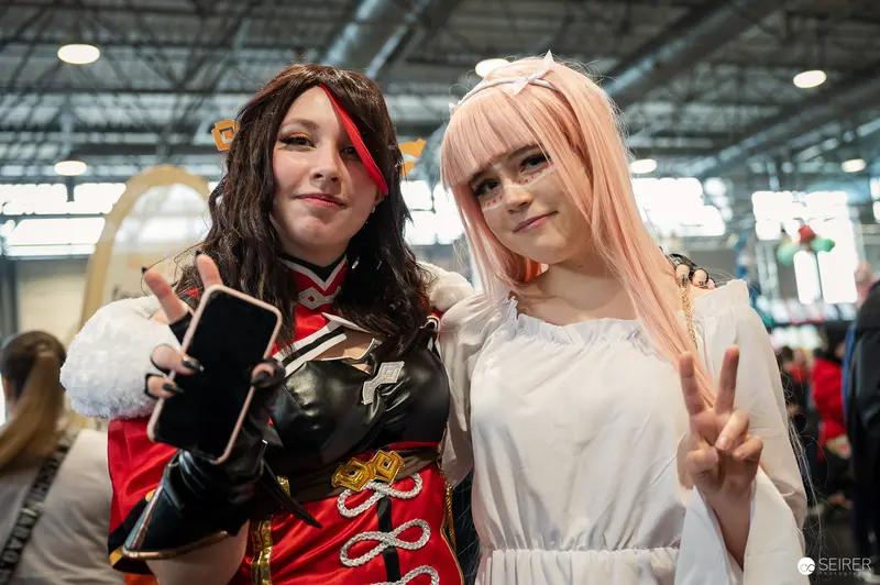 Vienna ComicCon 2023: Two Cosplayers Posing with Smartphone and Peace Sign