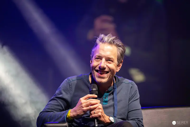 Comedian Performing Standup at Vienna ComicCon 2023 with Microphone and Warm Smile