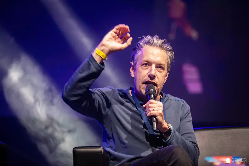 Energetic Speaker Gesturing During Panel at Vienna ComicCon 2023