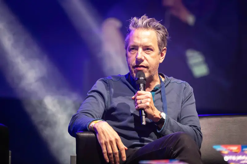 Contemplative Speaker at Entertainment Event Holding Microphone Under Blue Stage Lighting