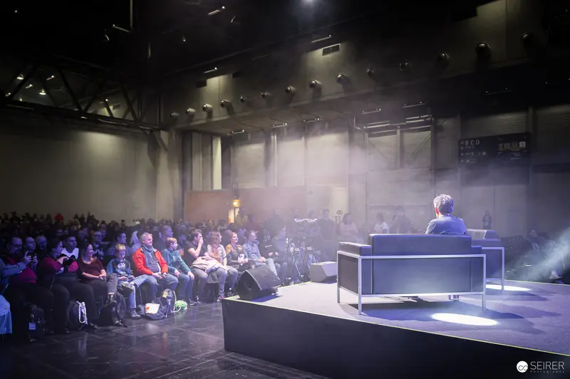 Presenter on Stage Amid Dramatic Smoky Atmospheric Lighting at Conference Event