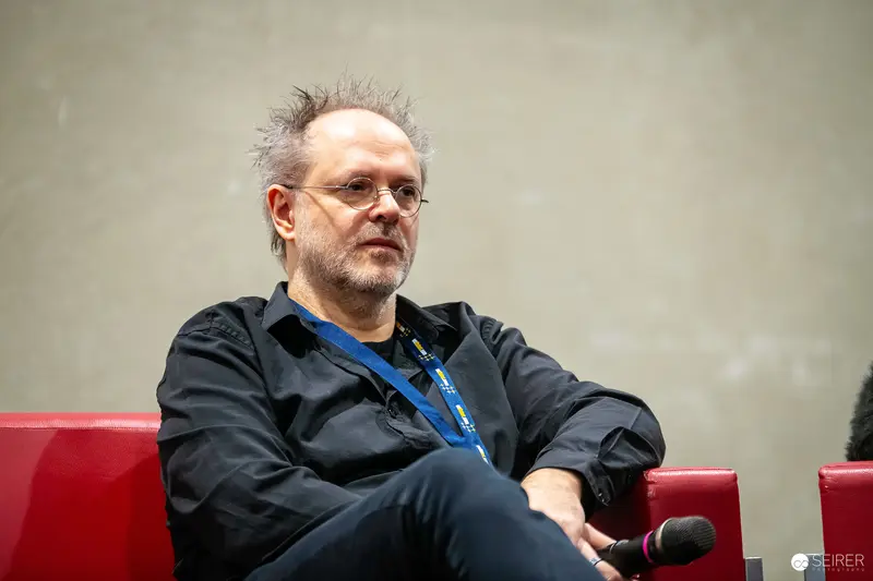 Seasoned Professional at Speaking Engagement Seated on Red Chairs
