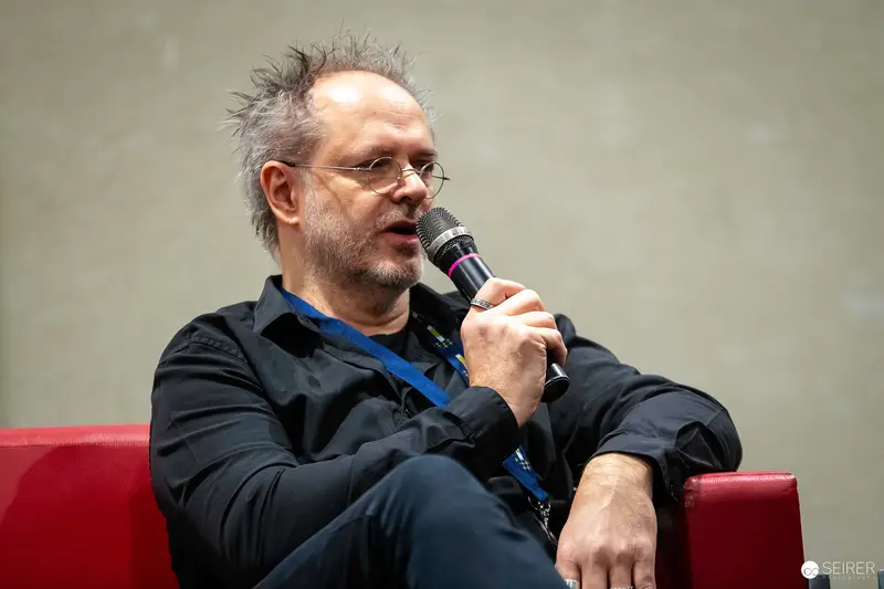 Speaker with Microphone at Vienna ComicCon 2023 Panel Discussion