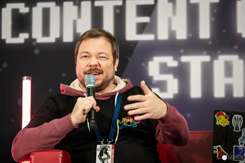 Comic Con Stage Presenter Engaging Audience with Microphone and Animated Gesture