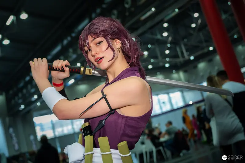 Cosplayer with Purple Hair Wielding Sword at Vienna ComicCon 2023