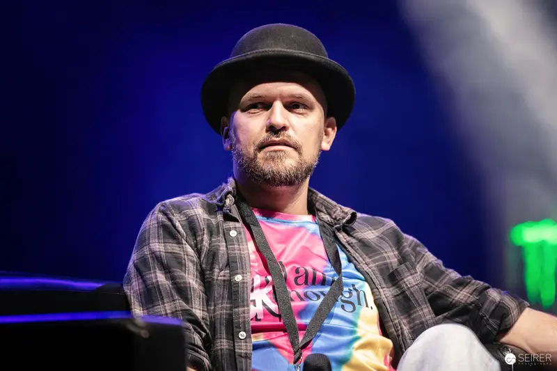 Artist in Plaid and Hat at Vienna ComicCon 2023 Stage Presentation