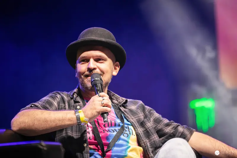 Comedian in Plaid Shirt and Hat Performing at Vienna ComicCon 2023