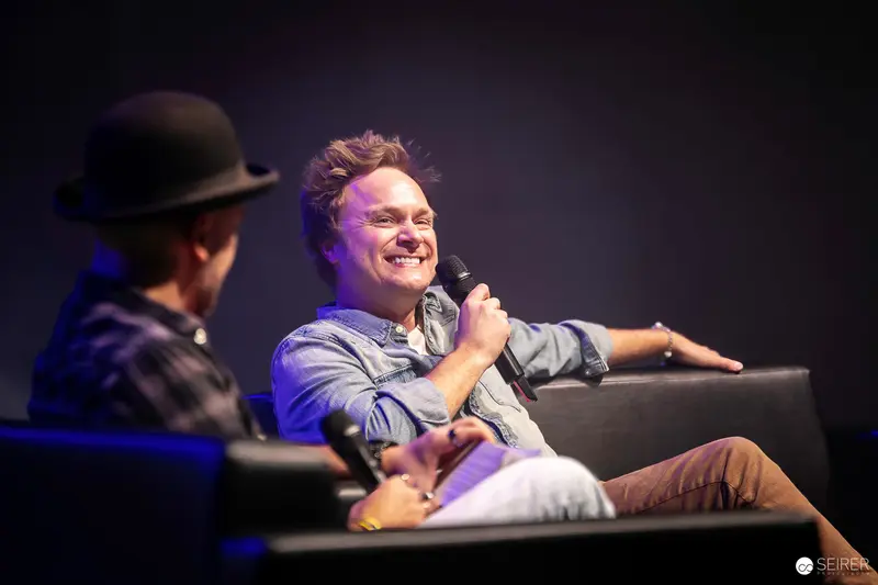 Smiling Performer Engaging in Animated Stage Interview at Comic Convention