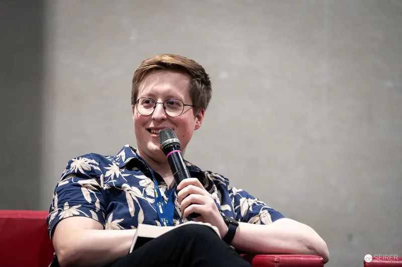 Vienna ComicCon 2023: Comedian Speaking on Red Stage with Microphone