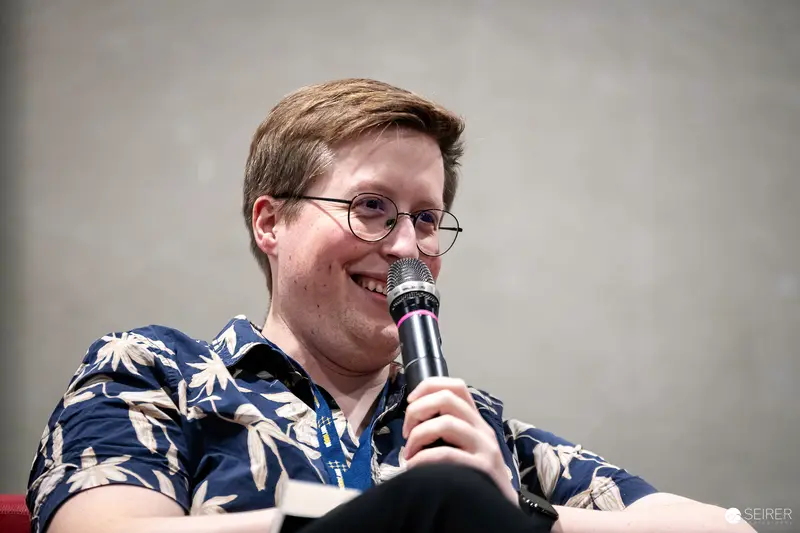 Enthusiastic Speaker in Floral Shirt at Vienna ComicCon 2023 Panel Discussion