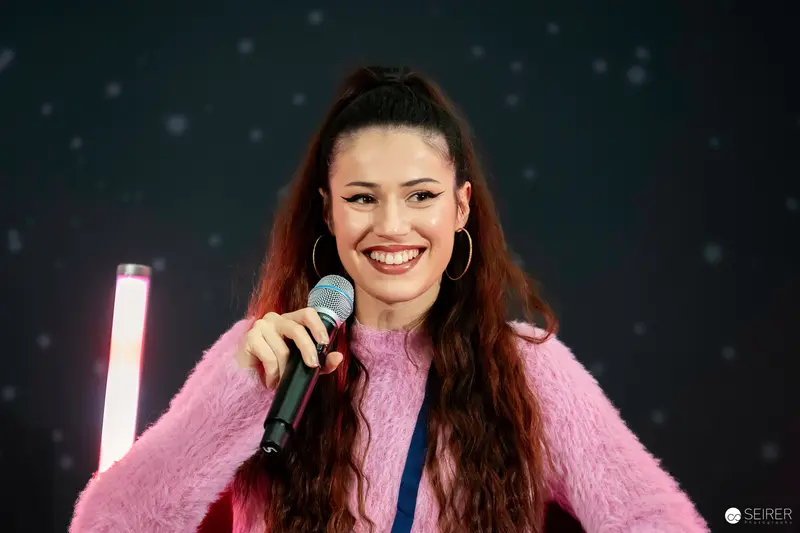 Smiling Performer in Pink Fur at Vienna ComicCon 2023 Microphone Stage