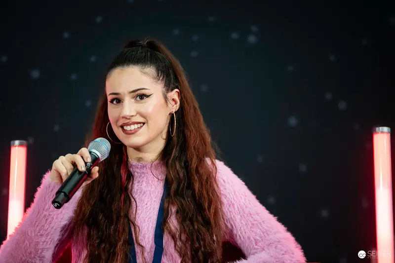 Performer in Pink Fuzzy Sweater Singing with Microphone at Music Event
