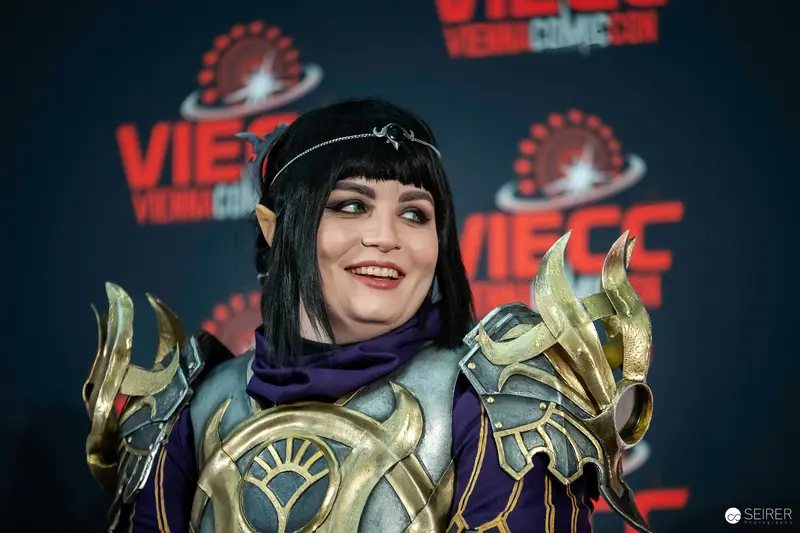 Cosplayer in Elaborate Armor Posing at Vienna ComicCon 2023 Event Backdrop