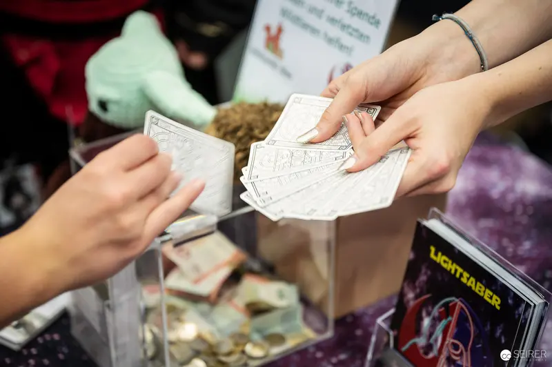 Comic Convention Transaction: Hands Exchanging Printed Materials at Vendor Booth